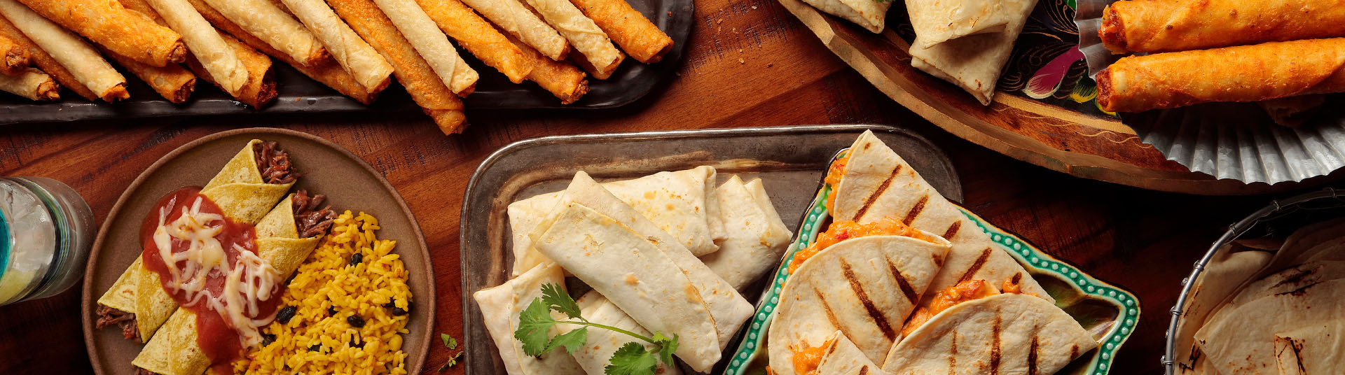 A table filled with El Monterey burritos, quesadillas, taquitos, and chimichangas.